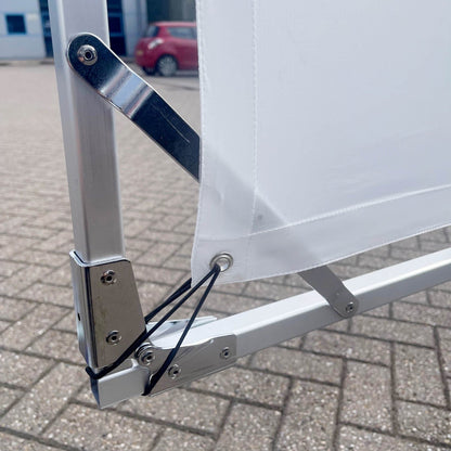 Close-up of a metal frame with a white sheet of diffusion in front of a paved surface.