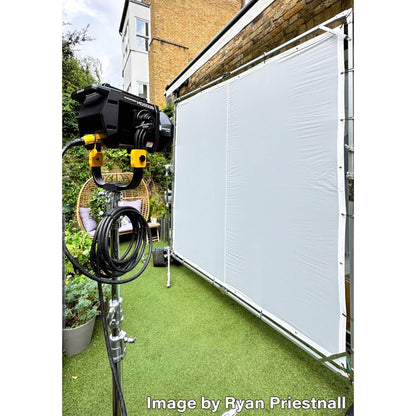 Outdoor setup with a camera and lighting equipment on a grassy area, shining through a PiXAPRO butterfly frame scrim diffuser. Image courtesy of Ryan Priestnall. 