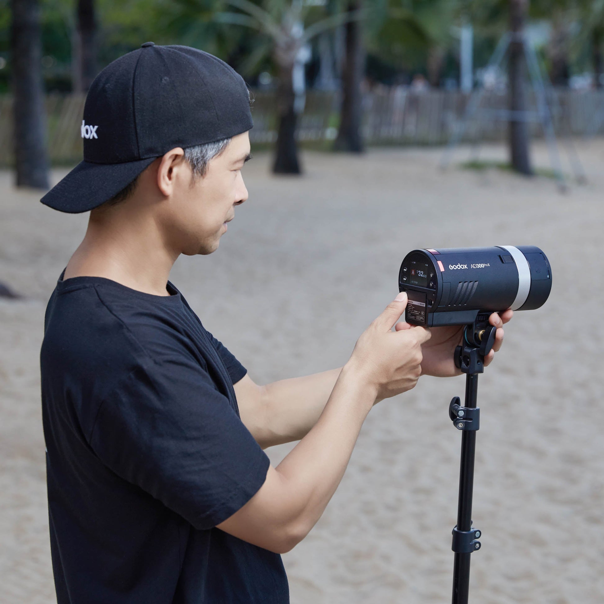A photographer inserting a battery into the back of a  Godox AD300proII Portable Battery Flash