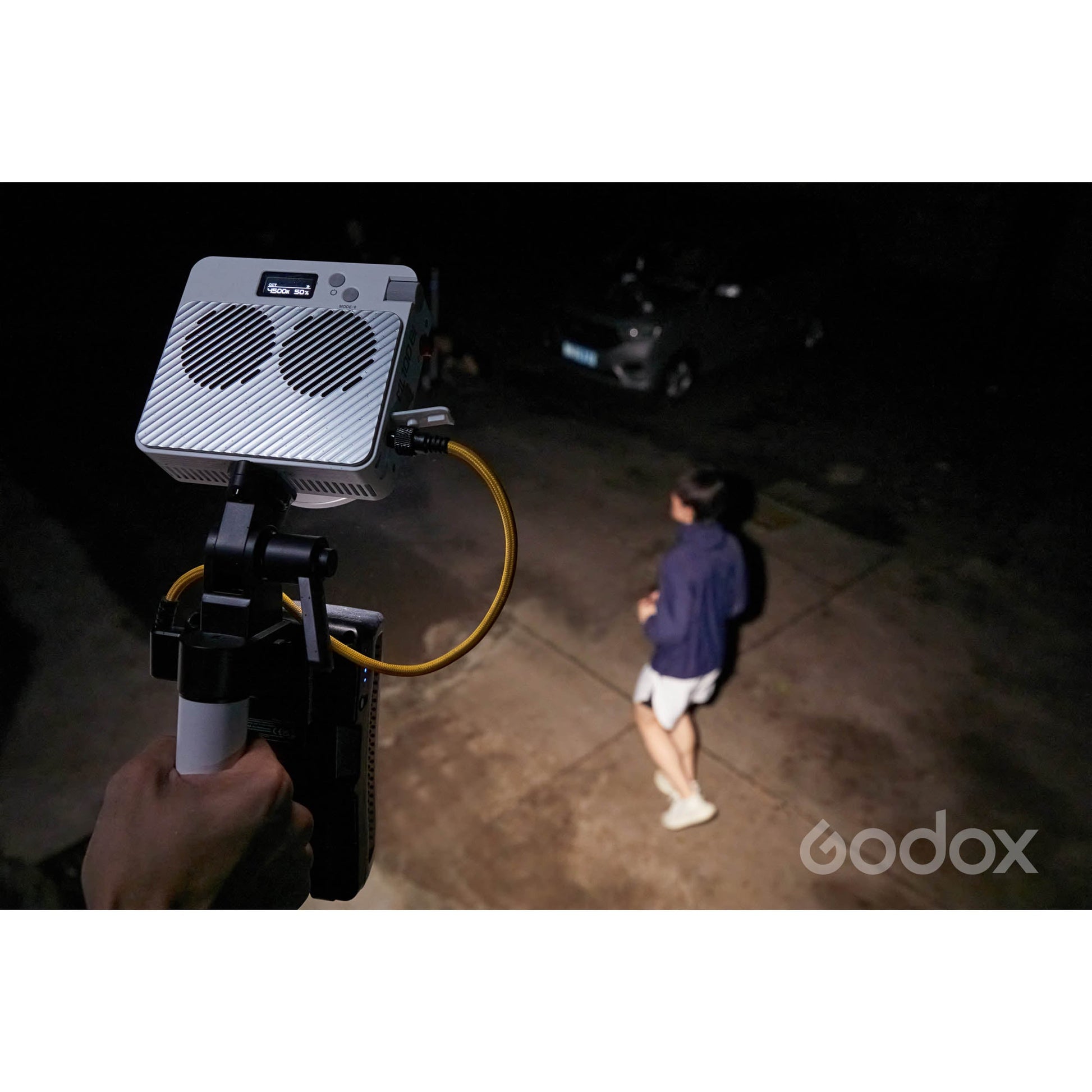 Godox ML60II Bi with AK-B02 adapter being handheld by a lighting assistant