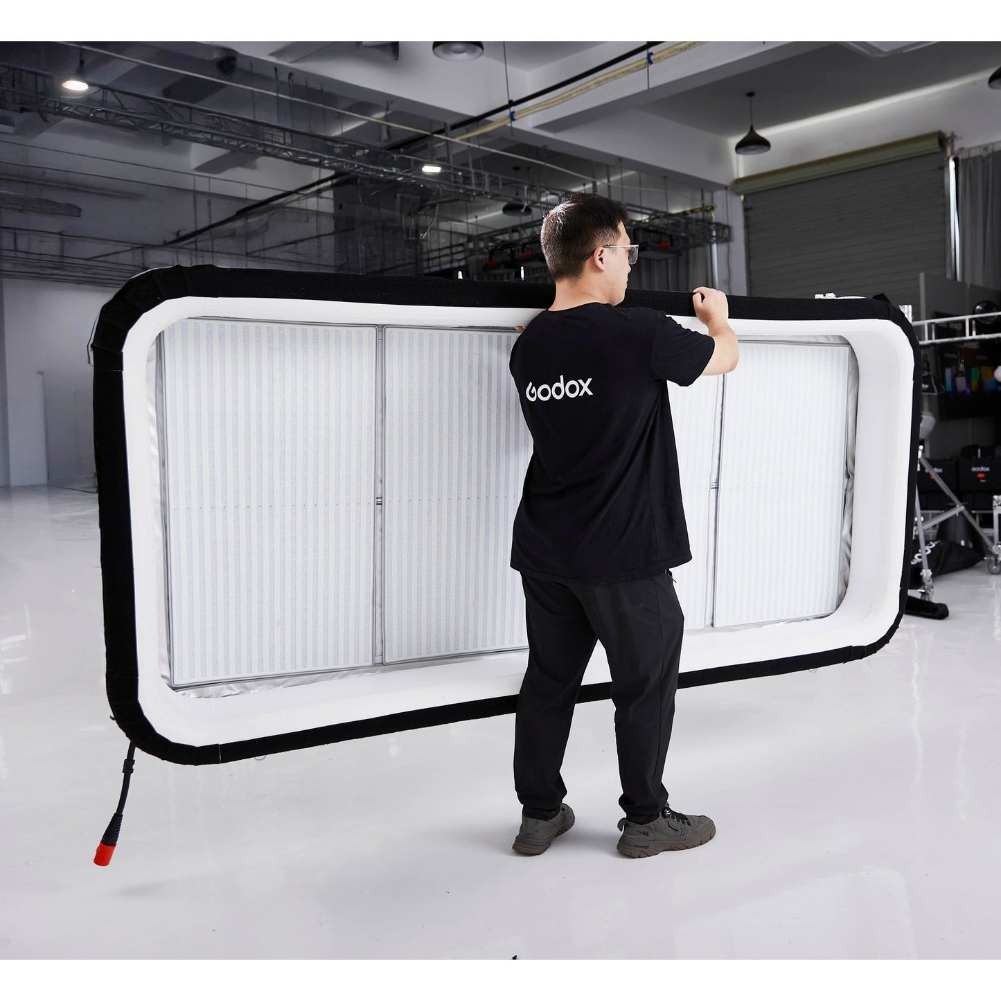 Gaffer carrying a Godox KNOWLED AM1600R-48K 4'x8' Inflatable RGB LED Light Mat