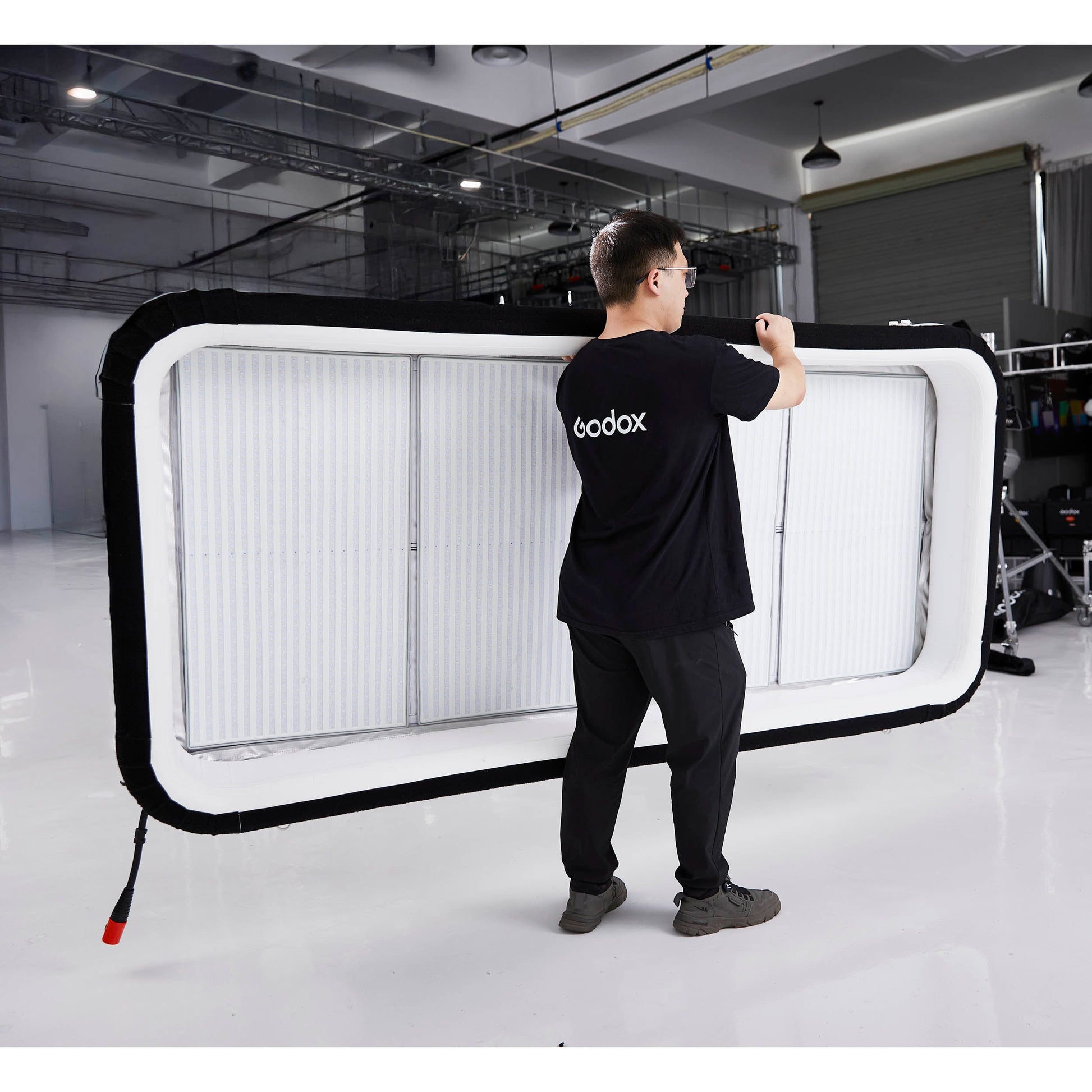 Gaffer carrying a Godox KNOWLED AM1600R-48K 4'x8' Inflatable RGB LED Light Mat
