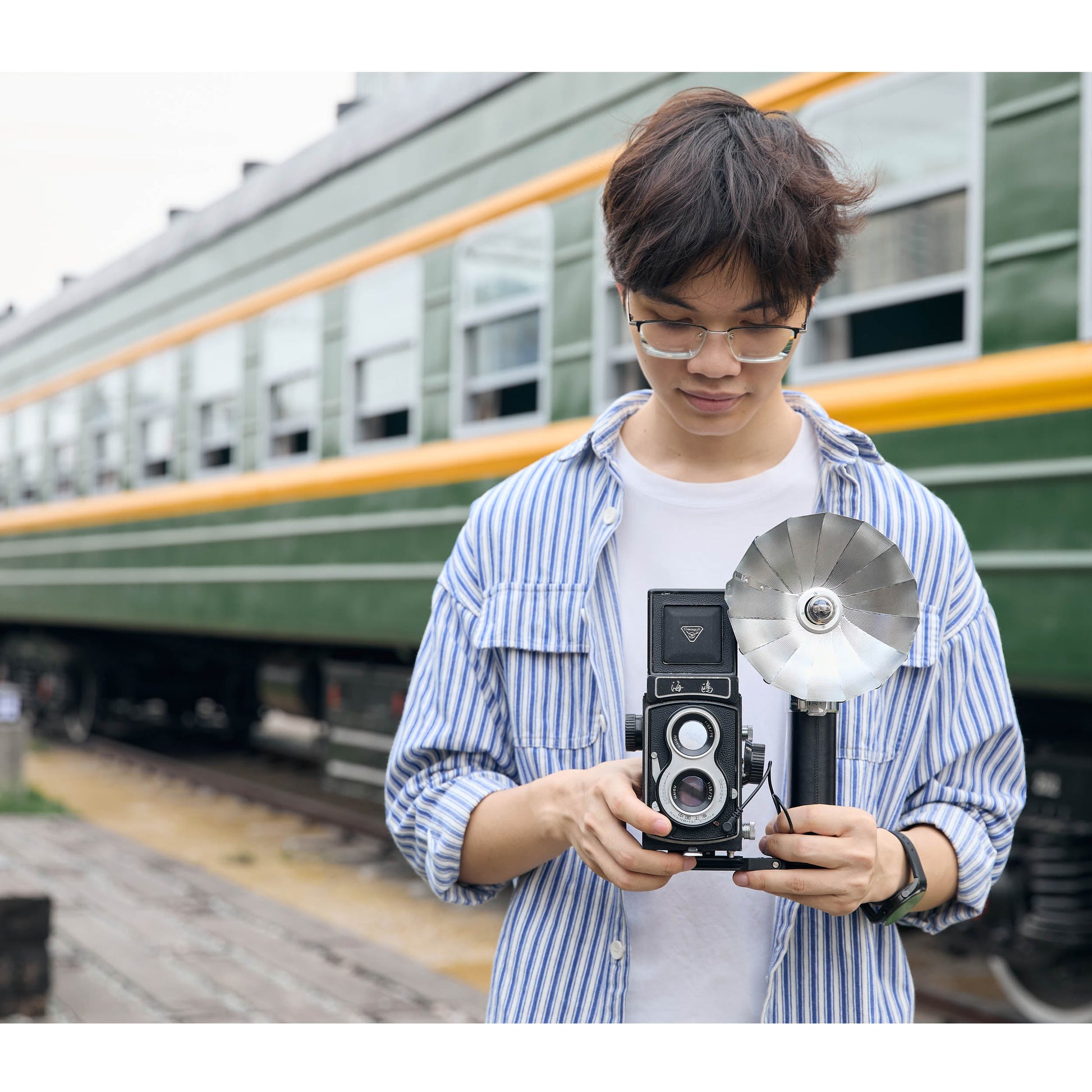 A photographer holding the LUX Master connected to an old Twin Lens Reflex Camera