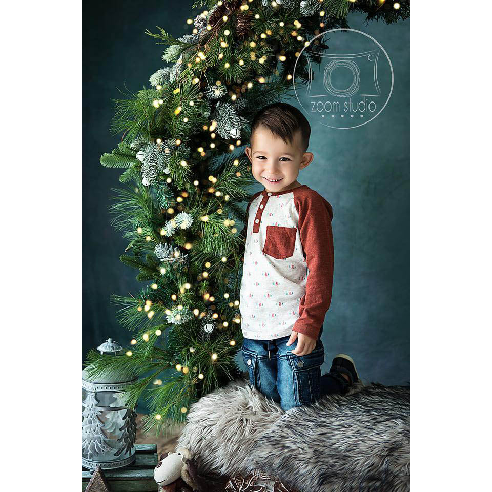 Child kneeling next to a decorated Christmas tree with lights on a dark background