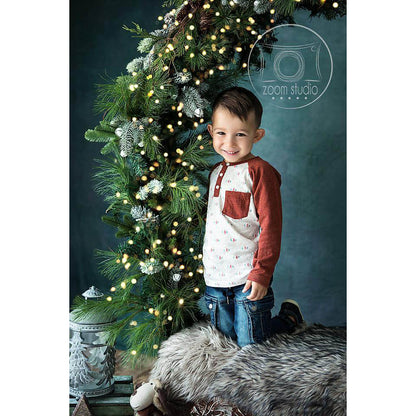 Child kneeling next to a decorated Christmas tree with lights on a dark background