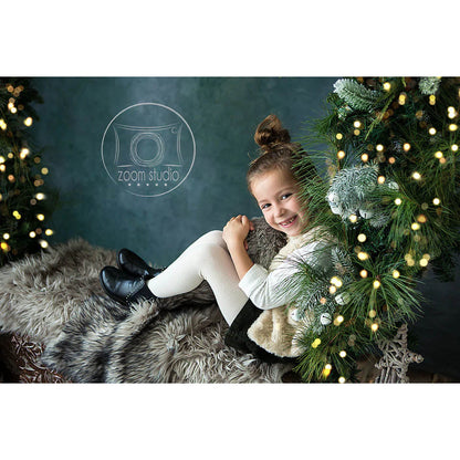 Young girl sitting on a fur rug with Christmas decorations and lights.