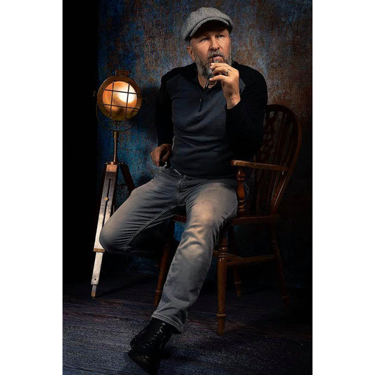 A man sitting on a wooden chair in a dimly lit room with a vintage lamp in front of a 2x3 Abstract Background Texture Studio Photography Background By Kate Backdrops