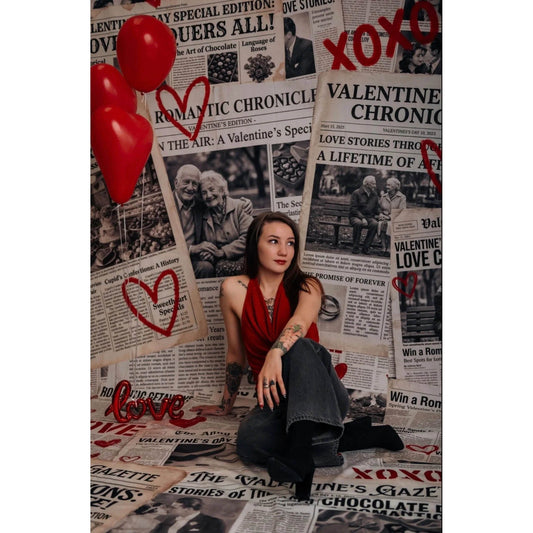 A young woman sitting in front of a Valentine's Day Newspaper Love Hearts Backdrop 